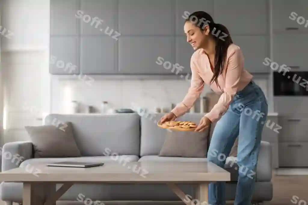 Baxtli ayol otish xonasida stolga tapsikdagi shirinliklarni joylashmoqda | Happy woman placing tray cookies table living room